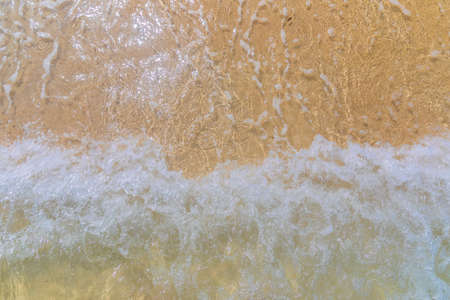 The wave rolls onto the sandy shoreの写真素材