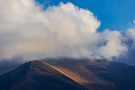 Light from the sun making its way through the clouds to the mountainsの写真素材