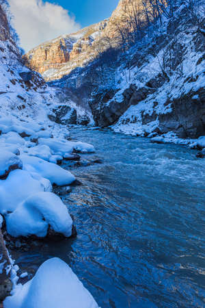 Mountain river flowing in the gorge in winterの写真素材