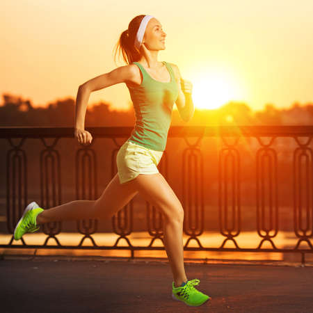 Running woman. Runner is jogging in sunny bright light on sunrise. Female fitness model training...