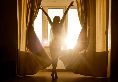 Woman in the morning. Attractive sexy woman with slender body is looking at the sunrise standing...