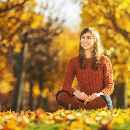 Beautiful happy young woman in the autumn park. Joyful woman is having fun outdoors in a bright yellow trees. Colorful fall concept.の写真素材