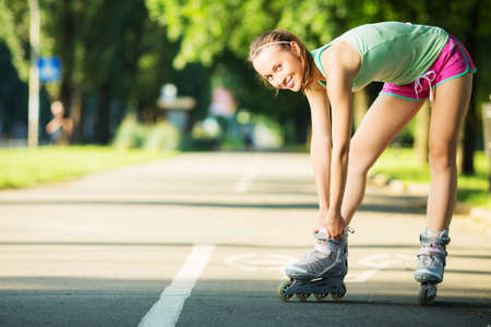 Rollerblading woman. Young attractive female fitness model is having fun skating in a city park in...