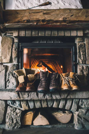 Winter boots in front of a fireplace.の写真素材