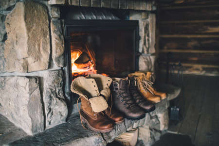 Winter boots in front of a fireplace.の写真素材