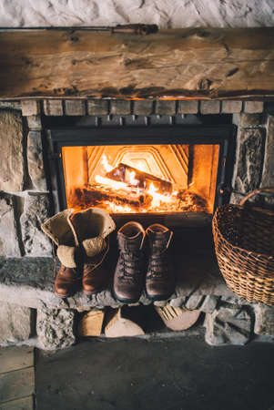 Winter boots in front of a fireplace.の写真素材