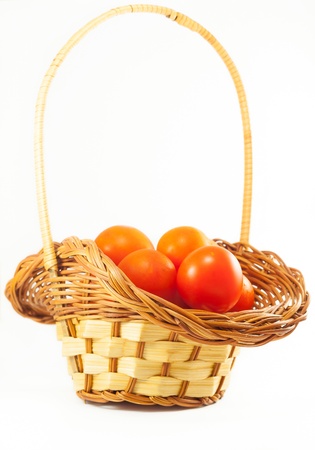 Cherry tomatoes in a basket, isolated on whiteの写真素材
