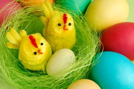 Colorful Easter eggs and two decorative chicks in a nest festive still lifeの写真素材