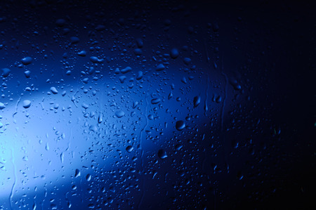 Wet glass with water droplets in blue light abstract artistic background textureの写真素材