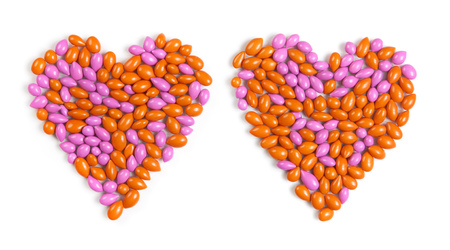Two hearts made by colorful dragee candies isolated on white backgroundの写真素材