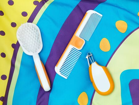 Brush, comb, nail clippers, set of baby grooming accessories on colorful fabricの写真素材
