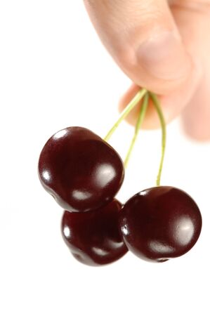 Three cherries in a hand close-up Isolated on white backgroundの写真素材