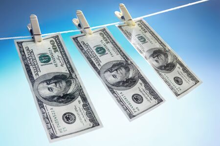 Hundred dollar bills drying on a clothes line isolated on blue sky background Money laundering conceptの写真素材