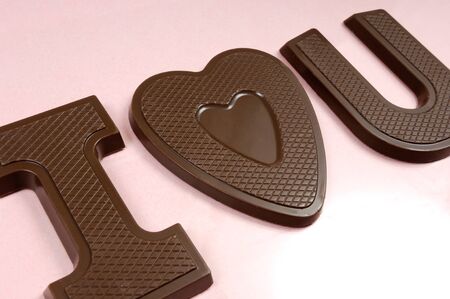 I love you spelled with letters and a heart made of chocolate Valentines Day concept Isolated on pink backgroundの写真素材