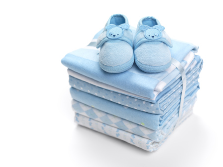 Cute blue baby boy shoes on a pile of swaddling blankets isolated on white backgroundの写真素材