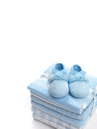 Cute blue baby boy shoes on a pile of swaddling blankets isolated on white backgroundの写真素材