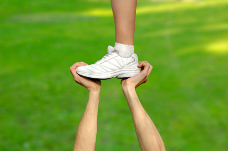 Two strong male hands holding one female foot. Teamwork, support, help, gymnastics, competition concepts.の写真素材