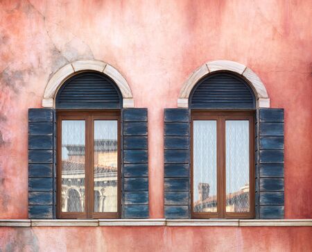 Wall with two old arched windows with shutters, rustic textureの写真素材