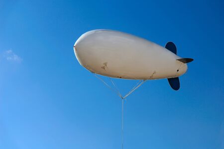 White inflatable airship hovering in blue clear skyの写真素材