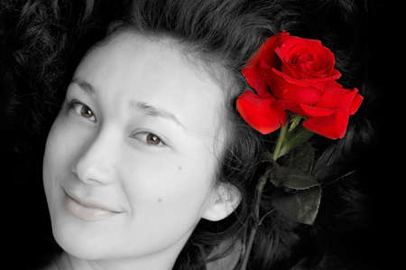 Beautiful young asian girl face with a red roseの写真素材