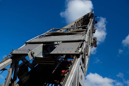 Steel fire truck ladder leading up into blue skyの写真素材