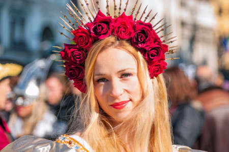 Portrait of a beautiful young blonde caucasian woman wearing a crown of red roses during the Venetian carnival party in San Marco squareのeditorial素材