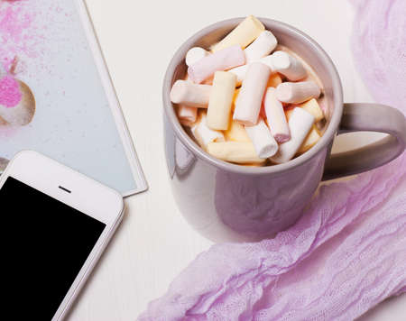 Mug coffee, cocoa with marshmallows and a phone on a white background