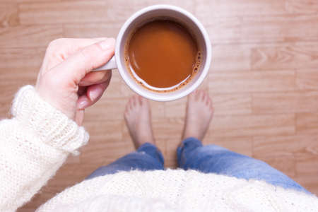 Girl, woman standing and holding a cup of coffee, top viewの写真素材