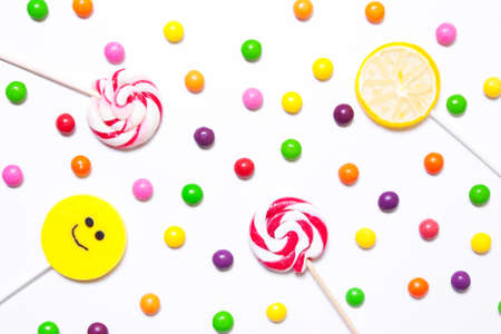 Lollipops, candy smile on, are scattered around the colorful jelly beans on a white background. flat.の写真素材
