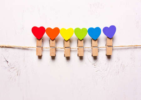 Wooden hearts of rainbow colors on clothespins on a white background. The symbol of LGBT