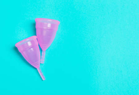 Two pink menstrual cup on a blue background. Concept of women's health, hygienic means of protection, menstruation, ecology of the planet.の写真素材