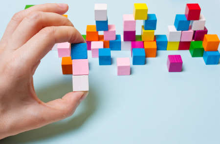 Blue, pink and white cube in hand. Concept of logical thinking, development, creativity, diversityの写真素材