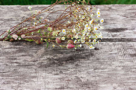 Field bouquet of flowers on the old wooden table, background
