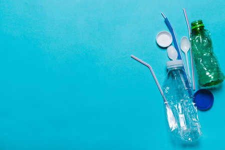 Plastic bottles, tubes, spoons, caps on a blue background. The concept of using environmentally friendly packaging, processing and sorting, preservation of the environmentの写真素材