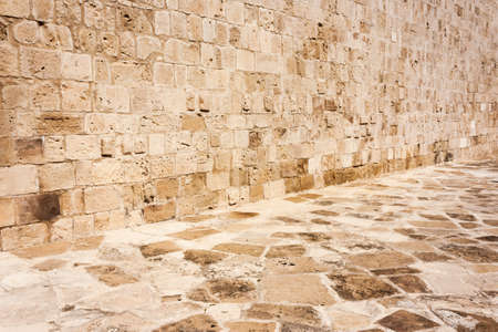 Old, brown, sandy, wall of a stone house in the open air. Seamless texture background rocks, bricksの写真素材