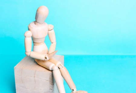 Wooden human figure on a blue background. The concept of pain in the abdomen, stomach, menstruationの写真素材
