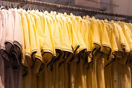 Men's clothing, fashionable, stylish on hangers in stores. The concept of shopping, sales. Yellow...