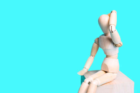 Wooden human figure on a blue background. Concept of pain in the head, problems
