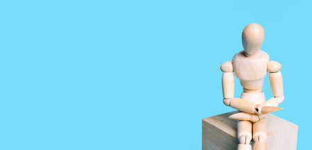 Wooden human figure on a blue background. Concept of art, creativity, courses, evolutions, minimal design. Copy space.の写真素材