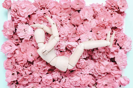 Wooden mannequin on a background of flowers. Depression concept,, sadness, problem