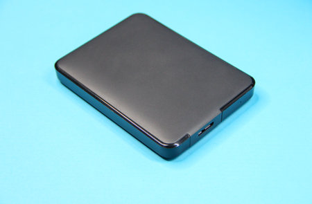 Black external hard drive on a blue background, copy spaceの写真素材