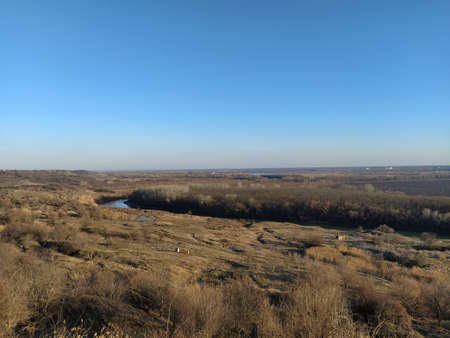 Autumn valley with river and trees against a blue sky