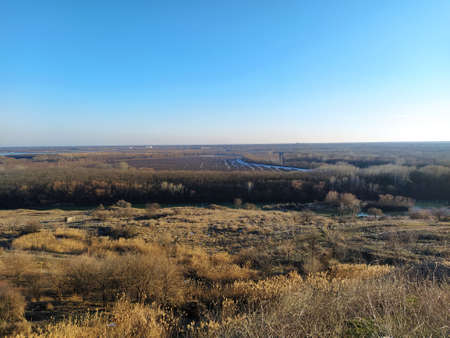 Autumn valley with river and trees against a blue skyの写真素材