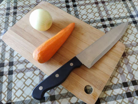 Vegetables carrot onion and knife on cutting boardの写真素材