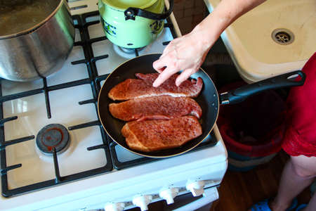 Woman fries pork chops with spices in the panの写真素材