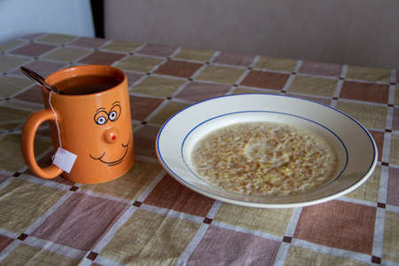 Plate of the oatmeal and cup of tea on the tableの写真素材