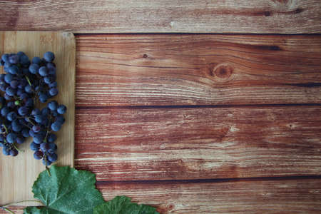 Blue grape bunches with leaves on brown wooden background with a copyspaceの写真素材