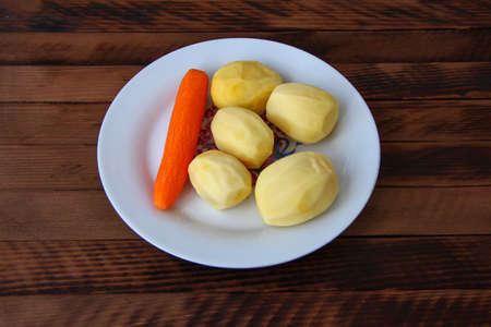 Raw carrots and potatoes on the plateの写真素材