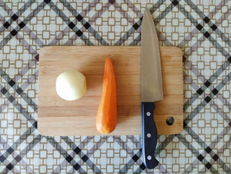 Vegetables carrot onion and knife on cutting boardの写真素材