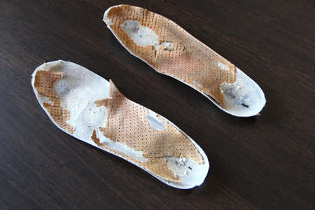 Two old, shabby orthopedic insoles on the tableの写真素材